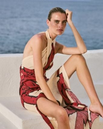 Johanna Ortiz model wearing a red and cream dress with ocean in the background