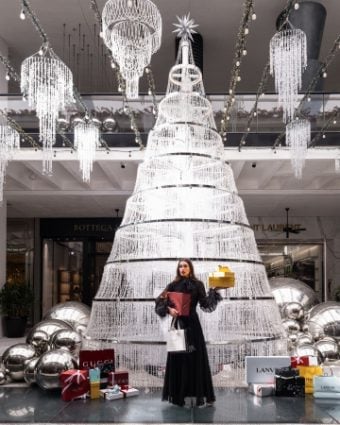 Model-wearing-black-dress-in-front-of-crystal-tree-boxes-and-shopping-bags