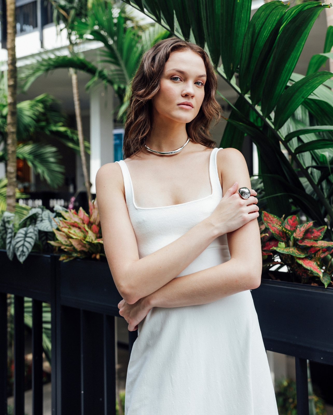Model wearing Scanlan Theodore white crepe knit dress surrounded by greenery