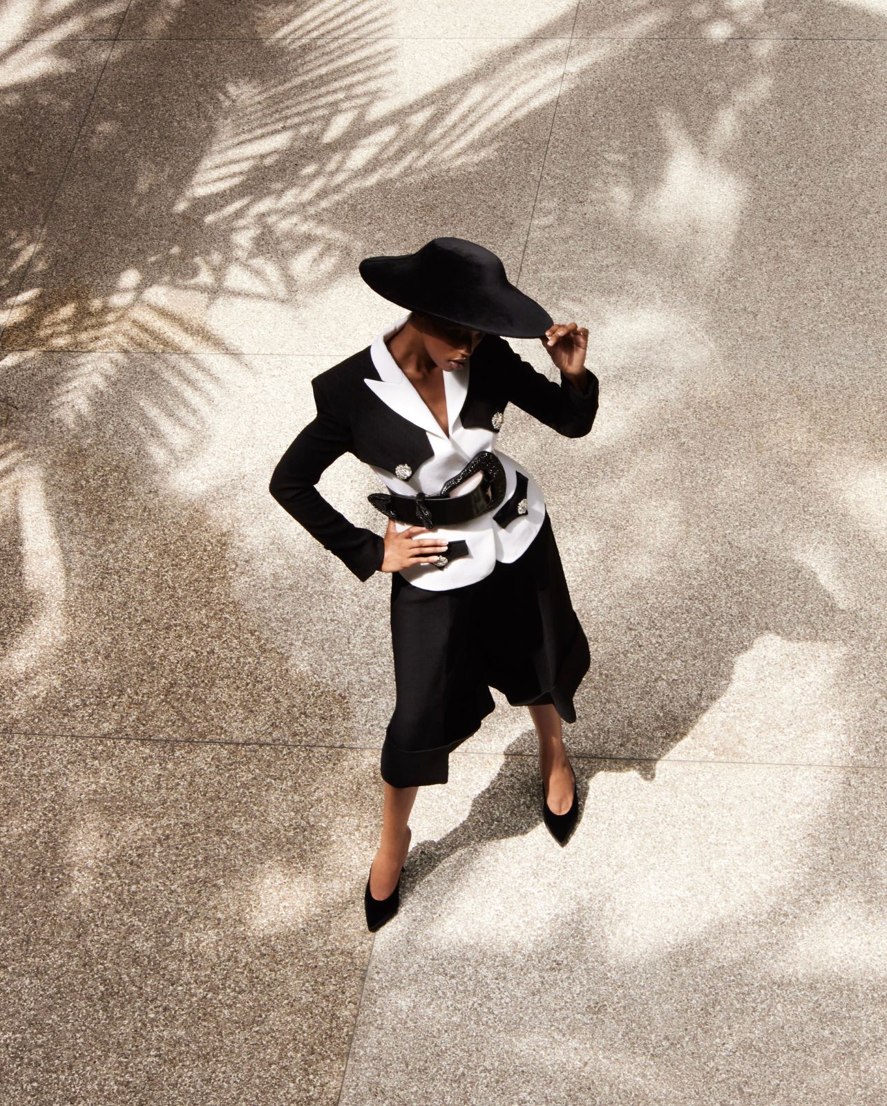 Model wearing Balmain black and white shorts and jacket suit with large black hat and black belt at Bal Harbour Shops