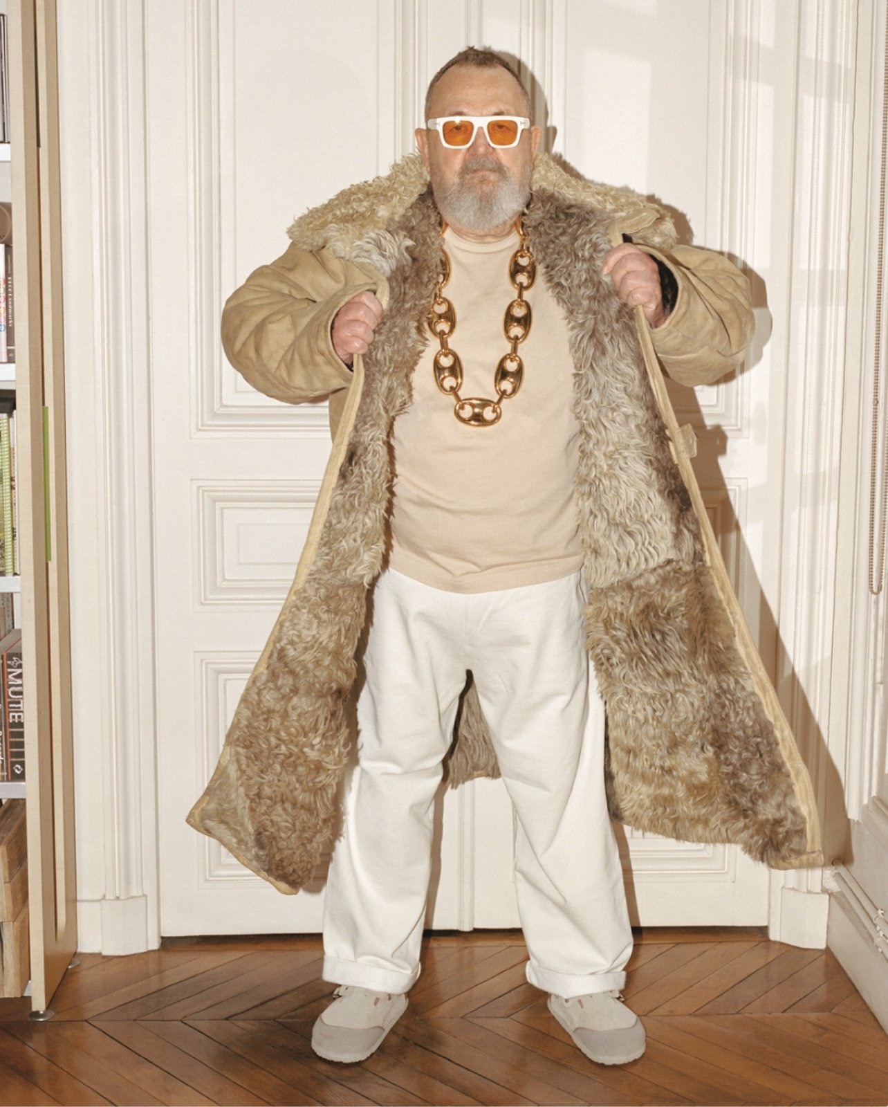 Michel Gaubert standing in a large sheepskin coat with a large golden chain and sunglasses