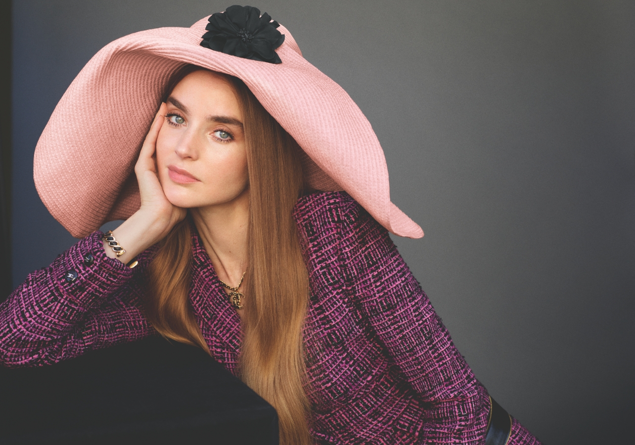 wearing Chanel pink tweed dress with large pink hat with black flower detail