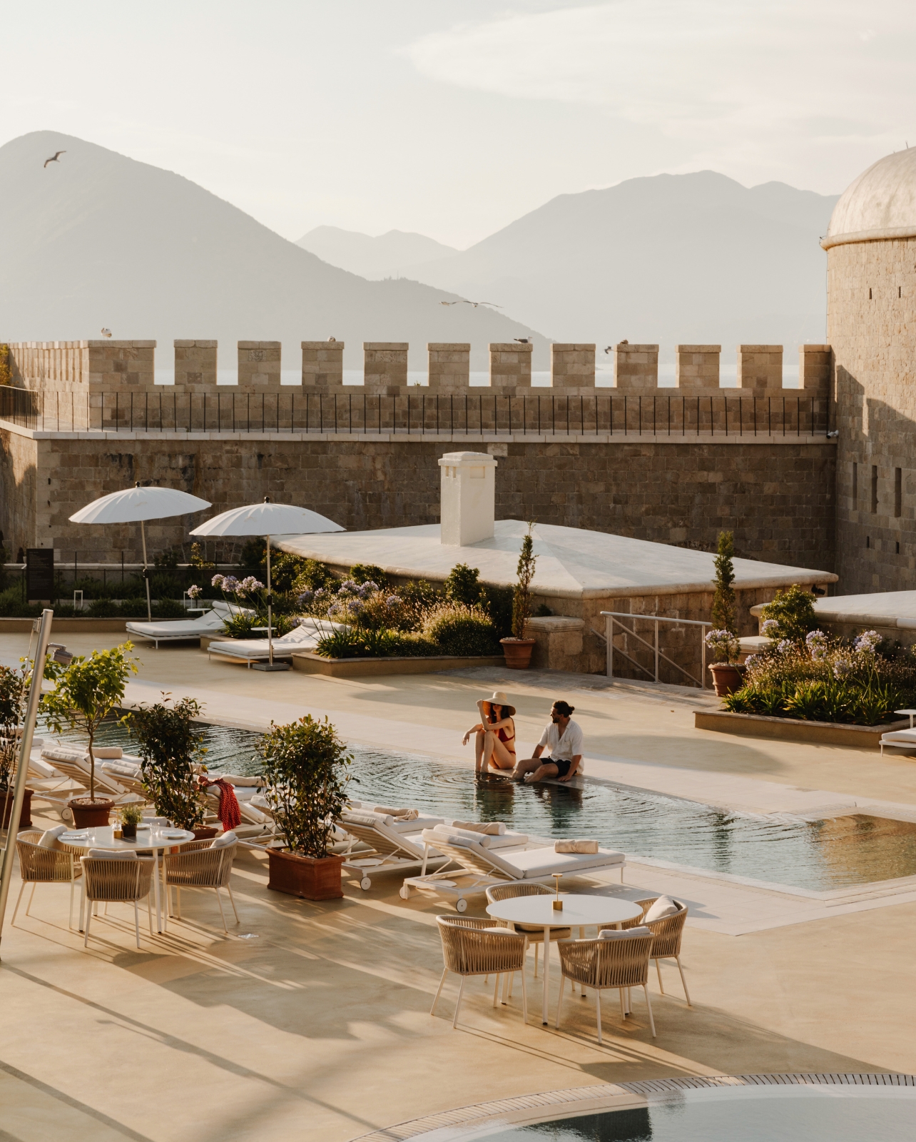 A couple sitting at the pool at Montenegro’s Bay of Kotor luxury resort