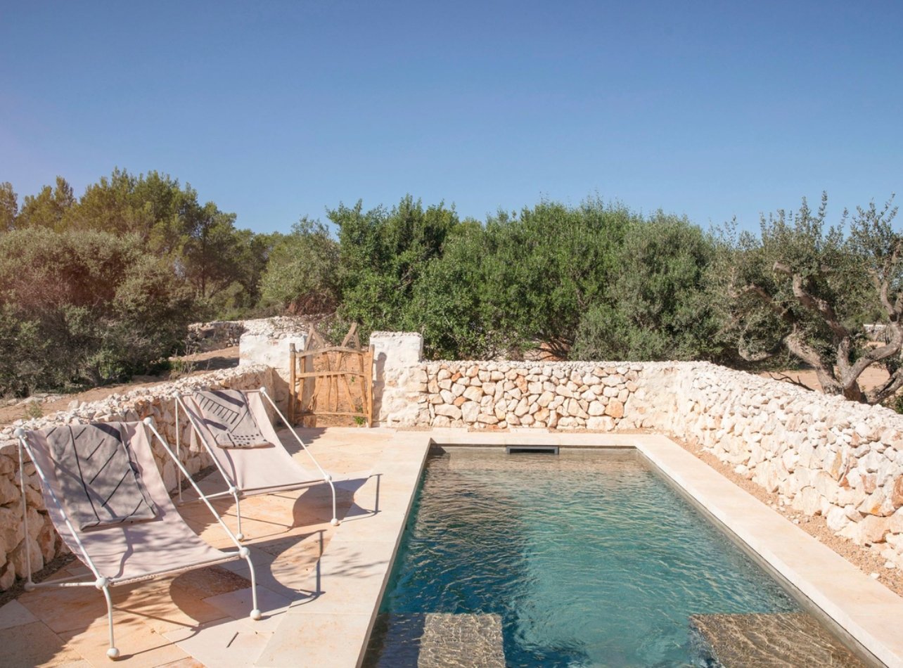 Pool with lounge chairs surrounded by a stacked rock wall