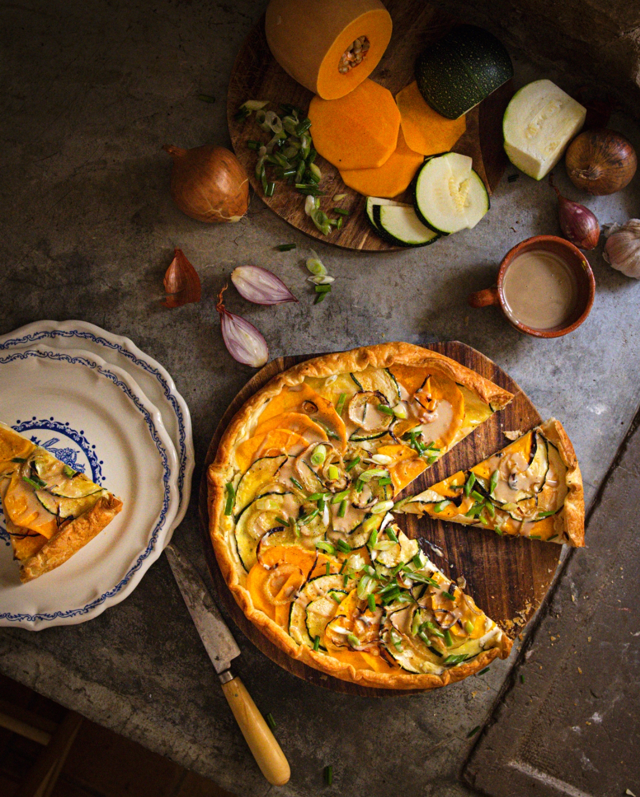 table with a full ricotta and squash galette with a smaller plate with a cut piece