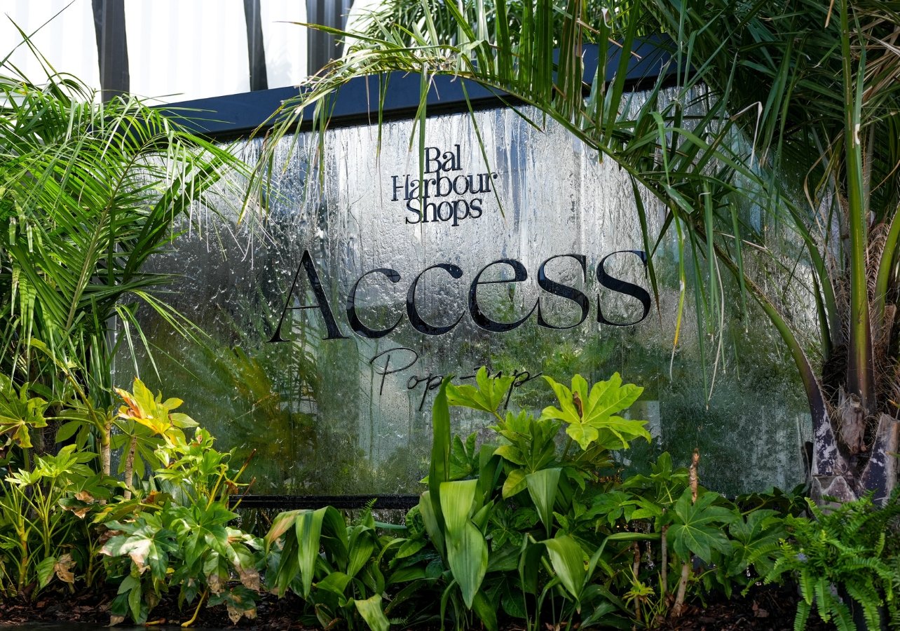 Bal Harbour Shops Access pop-up signage surrounded by greenery and a water fountain in the back