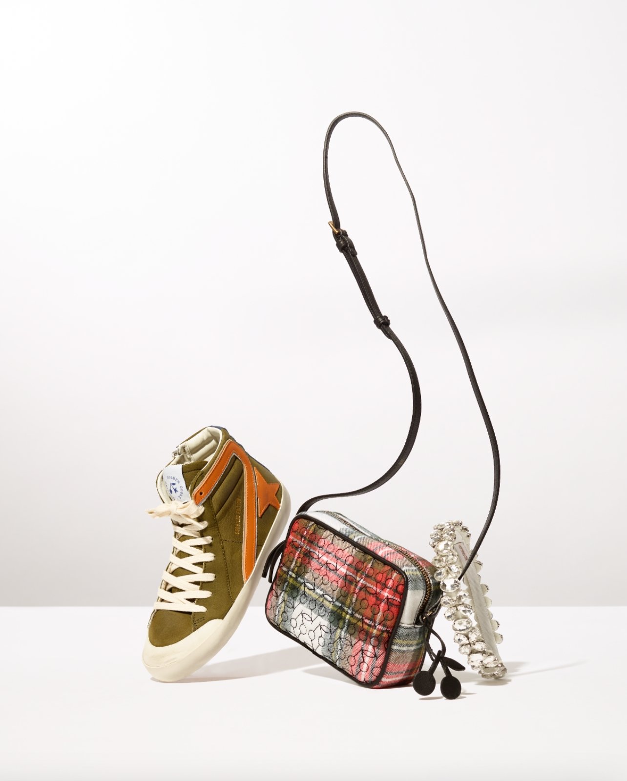 Gift Guide Image with a variety of items including a crystal headband, golden goose sneaker with orange and a bag