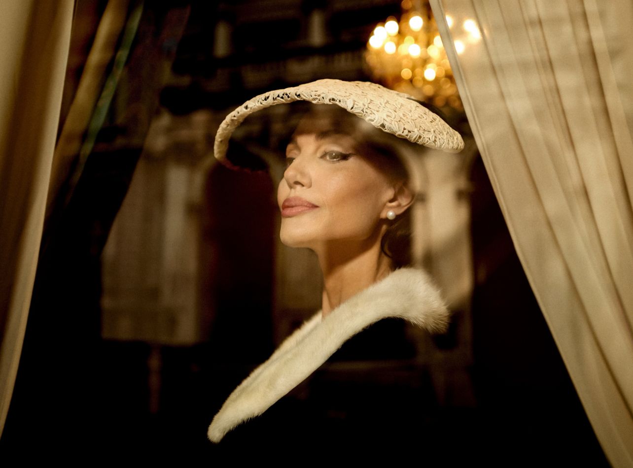 Angelina Jolie looking out of window wearing a white lace hat