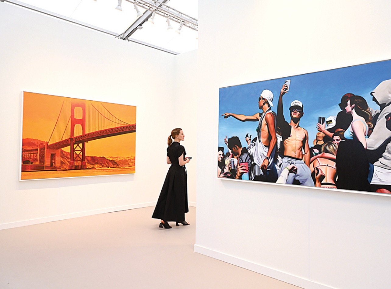 Woman in black walking through room that has two art pieces on white walls