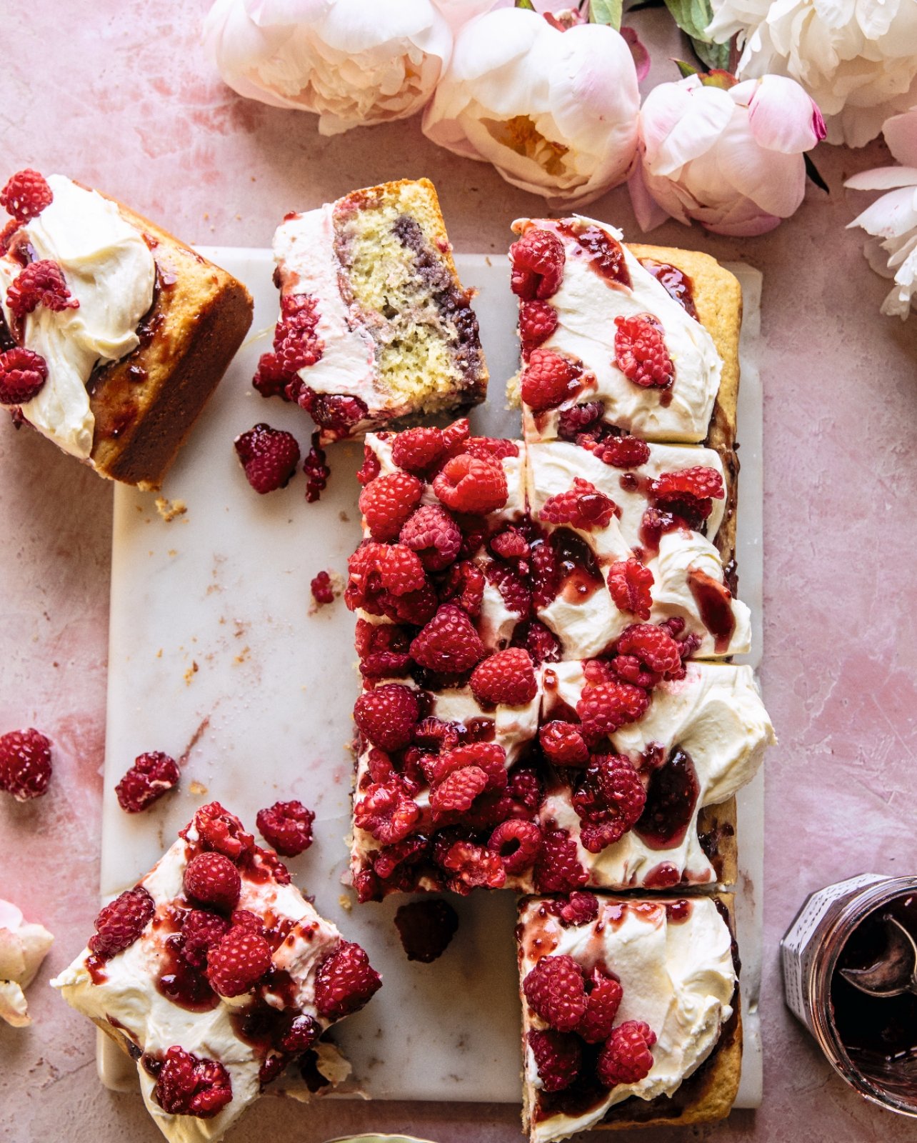 pink marble table with platter of cake covered in red raspberries