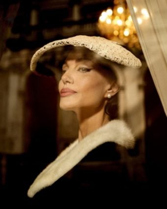 Angelina Jolie looking out of window wearing a white lace hat