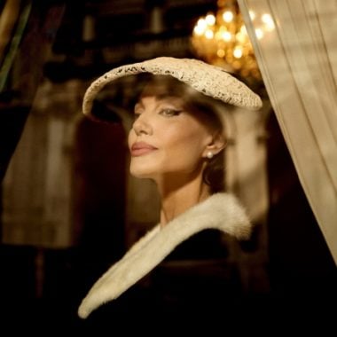 Angelina Jolie looking out of window wearing a white lace hat