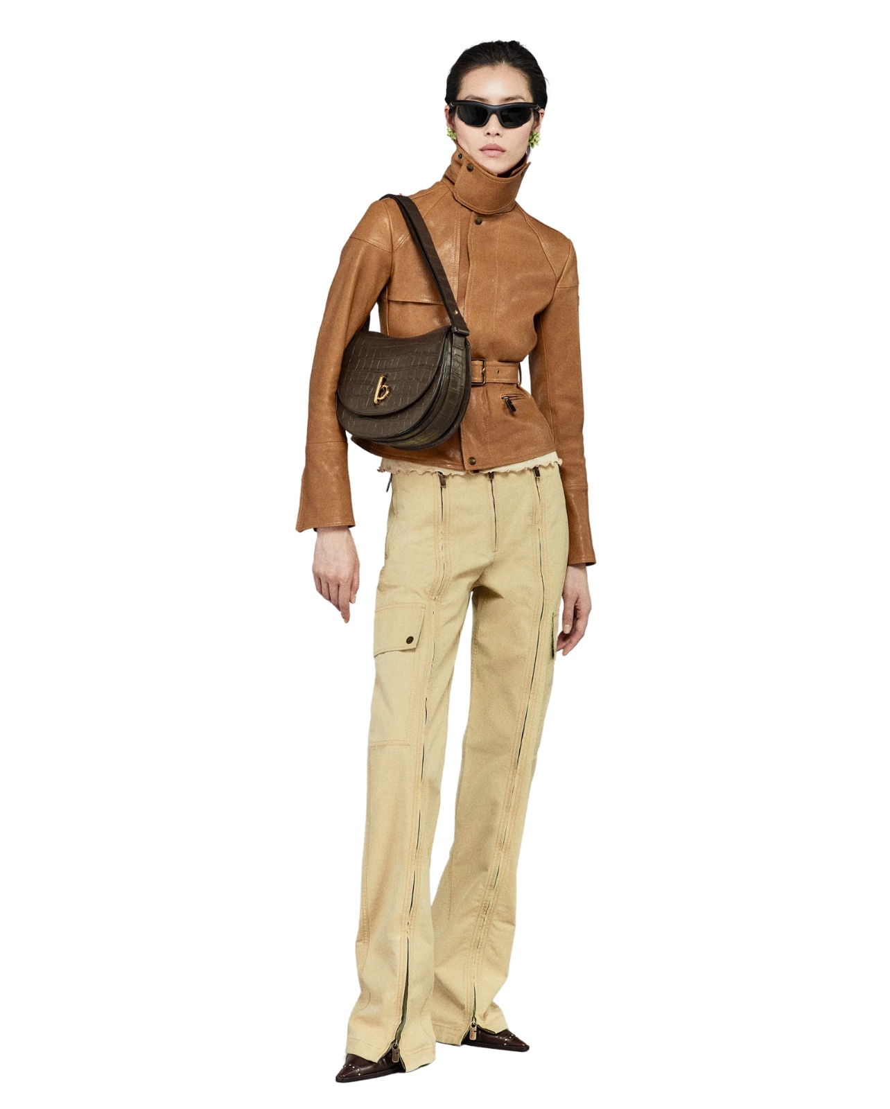 Burberry model wearing a brown leather jacket and yellow pants and a brown bag and sunglasses