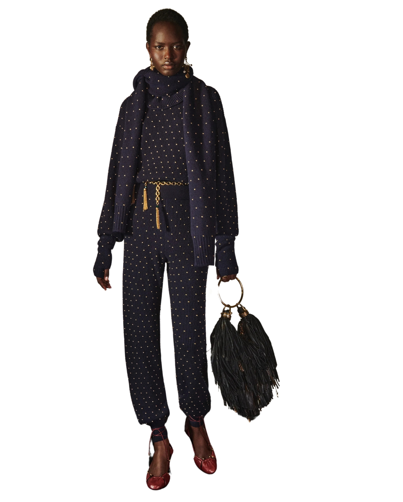 Chloé Model wearing a navy jumpsuit and jacket with gold gromets and a black fringe bag