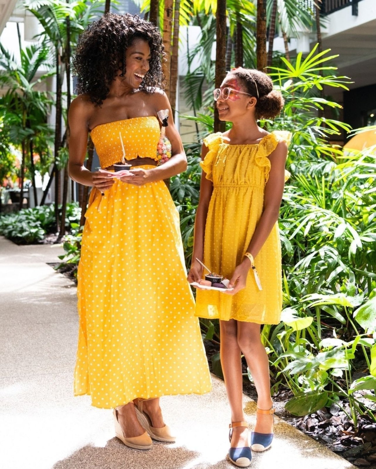 Woman and girl in yellow looks holding ice cream