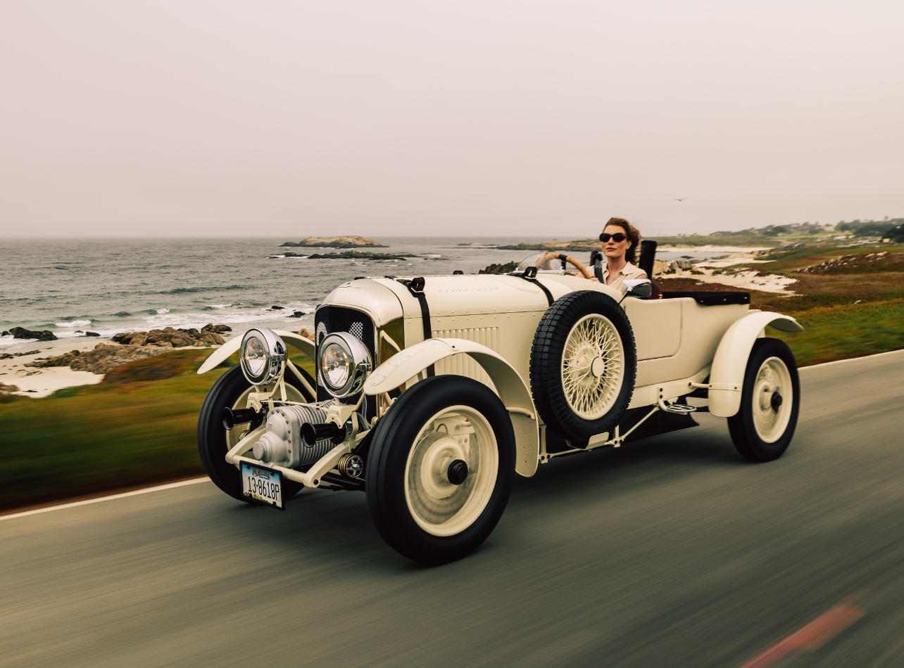 Woman driving a white car with ocean in the background