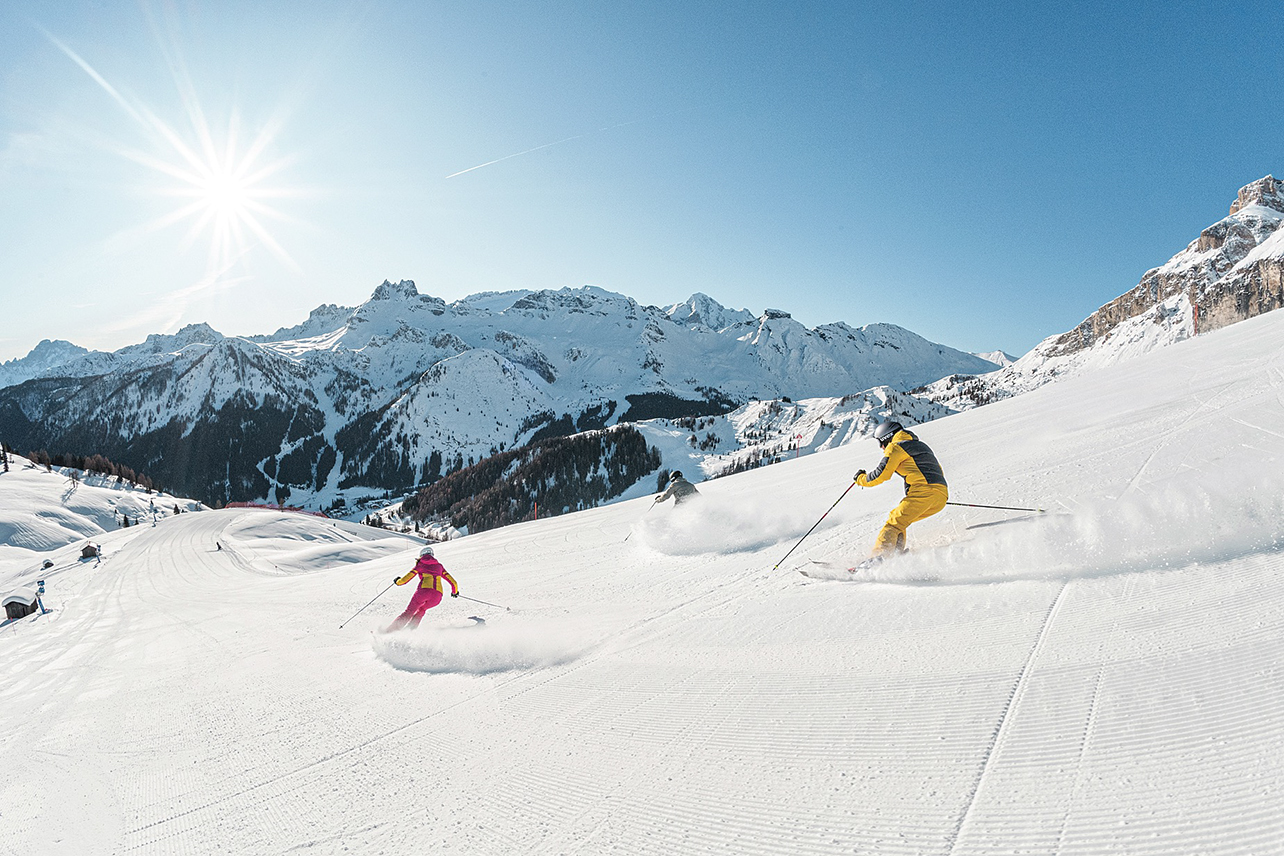 Two skiers going down slopes